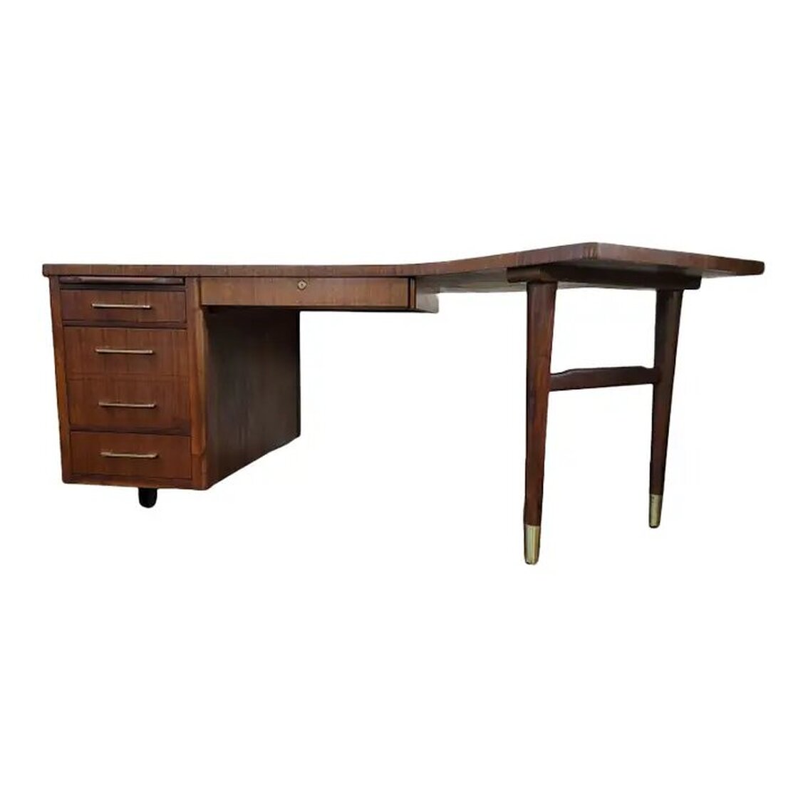 Vintage Boomerang Executive Desk was manufactured by the Alma Desk Company of High Point, North Carolina.  The desk is made of walnut wood with brass Art Moderne drawer pulls.  The burl walnut boomerang shaped top is trimmed with straight cut walnut veneer and rests upon two brass sabot footed walnut legs joined by a shaped stretcher at the right and a row of drawers at the left. The left side is supported by an ebonized stretcher foot.  The right-side legs may be adjusted to sit at an angle under the desk.  The left side features a pull-out shelf at top that was promoted by the company as able to hold up to 100 lbs., a shallow drawer, a file cabinet, and a bottom shallow drawer with side grooves for spacers.  At center is a single locking drawer. The lock is original to the piece and is numbered B614. When locked, all drawers in the desk are locked. The brass locking mechanism was made in the U.S.A. by the Chicago Lock Company. The desk comes with keys.  The case is constructed of straight cut walnut wood.