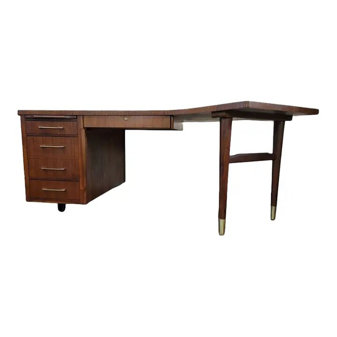 Vintage Boomerang Executive Desk was manufactured by the Alma Desk Company of High Point, North Carolina. The desk is made of walnut wood with brass Art Moderne drawer pulls. The burl walnut boomerang shaped top is trimmed with straight cut walnut veneer and rests upon two brass sabot footed walnut legs joined by a shaped stretcher at the right and a row of drawers at the left. The left side is supported by an ebonized stretcher foot. The right-side legs may be adjusted to sit at an angle under the desk. The left side features a pull-out shelf at top that was promoted by the company as able to hold up to 100 lbs., a shallow drawer, a file cabinet, and a bottom shallow drawer with side grooves for spacers. At center is a single locking drawer. The lock is original to the piece and is numbered B614. When locked, all drawers in the desk are locked. The brass locking mechanism was made in the U.S.A. by the Chicago Lock Company. The desk comes with keys. The case is constructed of straight cut walnut wood.