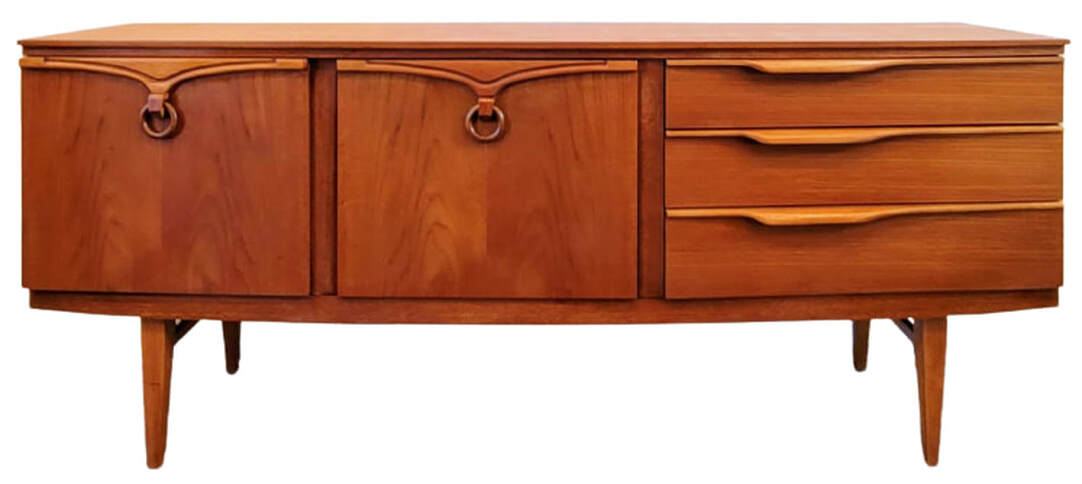 Beautility bow-front sideboard on squared and tapered legs with side stretchers. The carcase is of new growth teak wood with the door fronts of Southeast Asian crown-cut teak. On the left is a single door cabinet containing one standard shelf. In the center is a fall-front cocktail cabinet containing one standard shelf. On the right are three drawers. The top drawer is lined and contains adjustable spacers for flatware storage.
