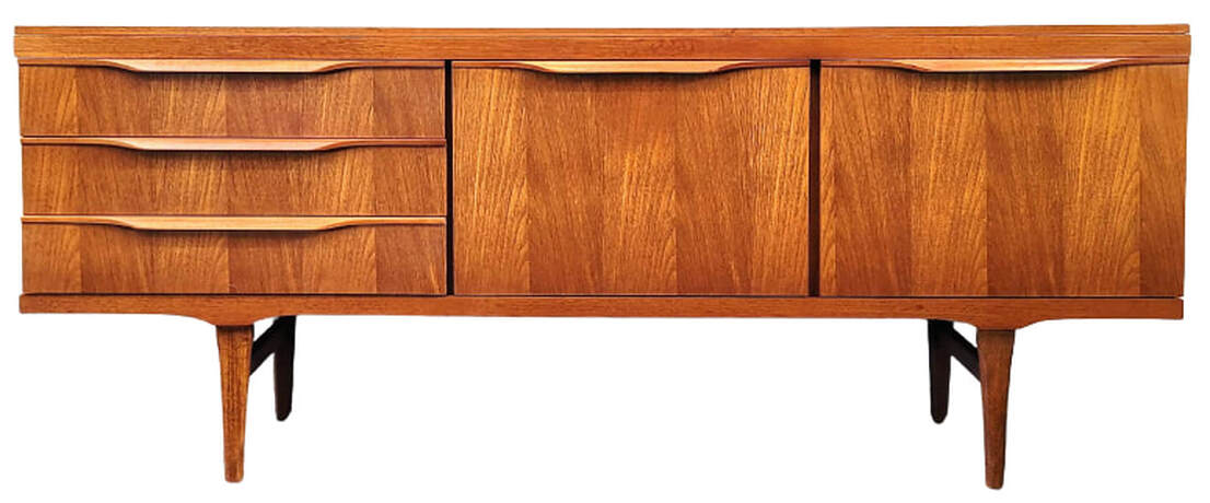 Elliott's of Newbury vintage teak credenza is on tapered legs with side stretchers. The carcase is fitted with three drawers on the left. To the right of the drawers is a rare double cocktail cabinet with two fall-front doors.