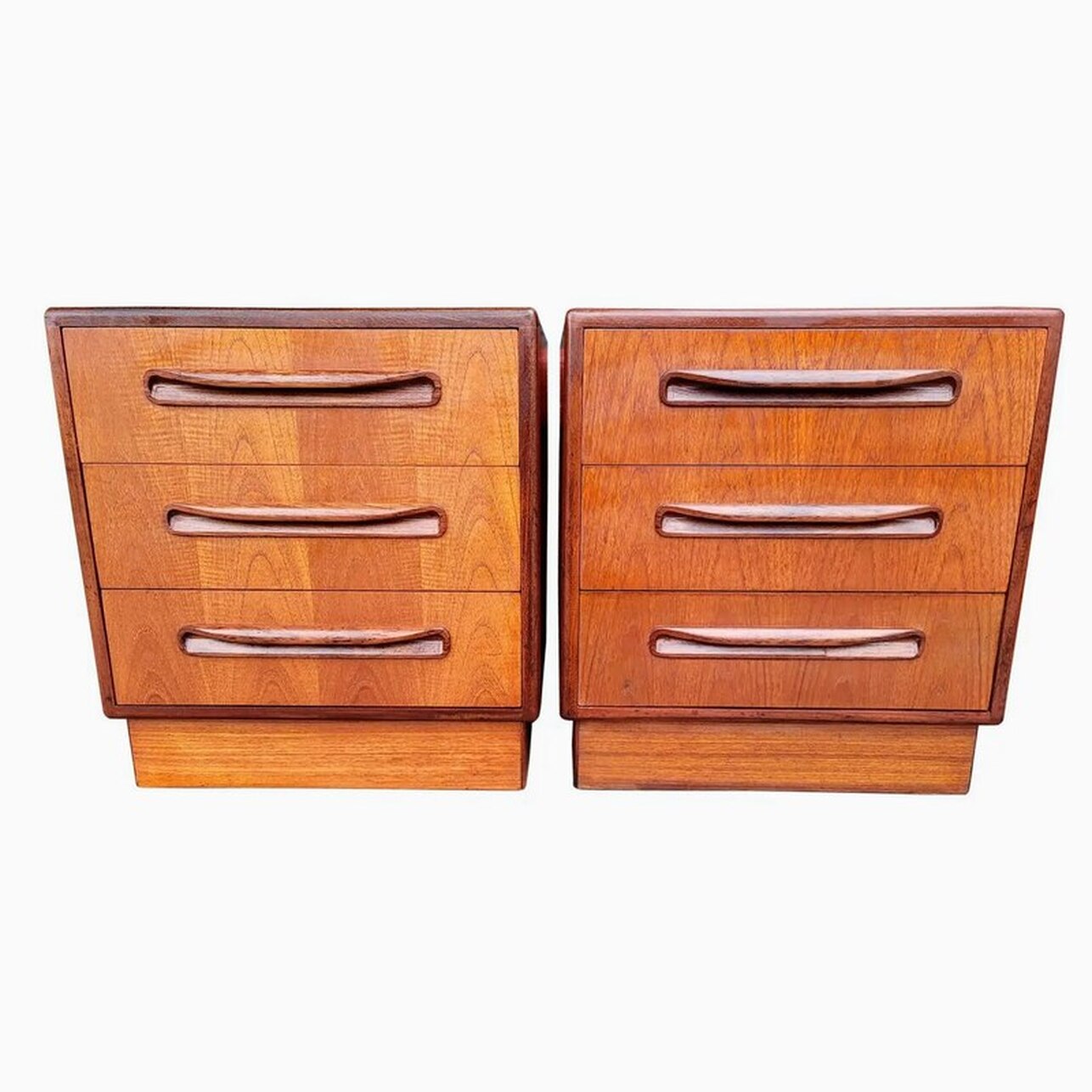 Pair bedside chests with three storage drawers surmounting plinth bases.  Teak veneers with solid afrormosia wood trim and pulls.  Designed by Victor Bramwell Wilkins for the E. Gomme G-Plan Fresco Range.