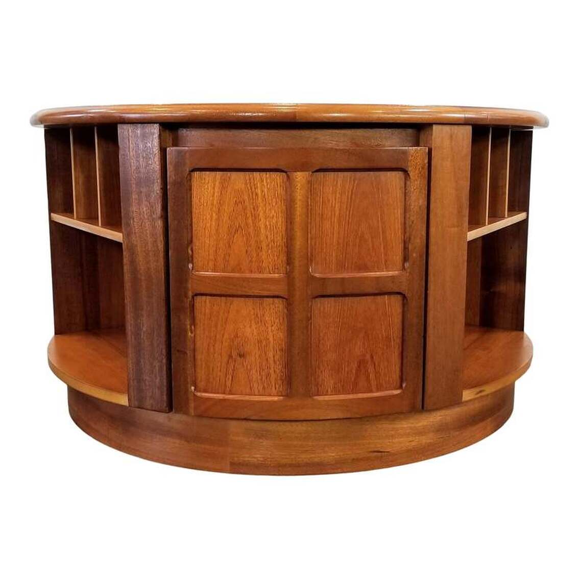 Nathan round table with cabinets and shelves. Suitable as a cocktail or coffee table. Jacobean inspired simplified cruciform framed paneling on the doors designed by Patrick Lee for Nathan Furniture in 1971. This design was an instant hit when it debuted and has remained an icon of Nathan Furniture collected by generations. Nathan Furniture uses sustainably sourced Tectona Grandis. The company chooses the teak for its quality and character in order to present perfectly matched veneers that showcase special beauty and individuality. The table is on casters for ease of movement.