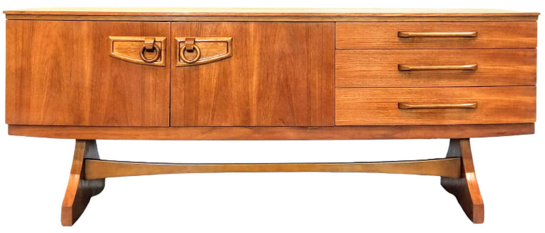 Bow front Beautility teak sideboard has a cabinet on the left, a cocktail cabinet in the center, and three storage drawers on the right. The cabinet pulls are signature Beautility drop ring pulls. The carcase surmounts a trestle base.