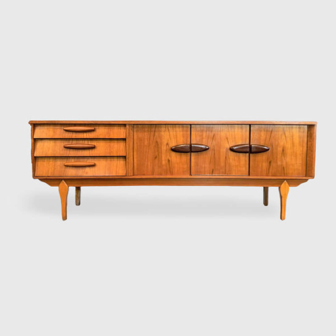 Beautility sideboard has a carcase constructed from Southeast Asian crown-cut new growth teak. The inverted teardrop legs are birch wood. On the left front are three stepped drawers with mini-baguette shaped teak pulls. In the center is a single-door cabinet and a cocktail cabinet. On the right front side is another single-door cabinet. The cabinets all have half-ellipse pulls that appear to be Ipe wood ( Brazilian Walnut ).