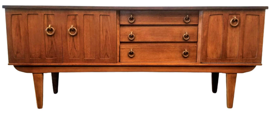 Mid-Century UK Modern Southeast Asian crown-cut young teak credenza with a strip of African afrormosia wood across the top edge. Wooden ring pulls open the draws and cabinets.  Sideboard features a two-door cabinet on the left, three draws in the middle, and a cocktail cabinet on the right.