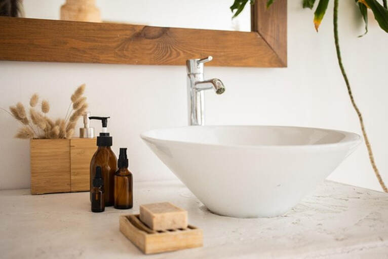 Sink with mirror bottles of soap and cosmetic oil in bathroom